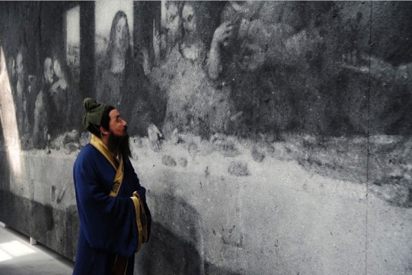 An actor portraying Confucius alongside The Last Supper of Mankind, a work in incense ash. Both are part of the Zhang Huan exhibition of Q Confucius. 